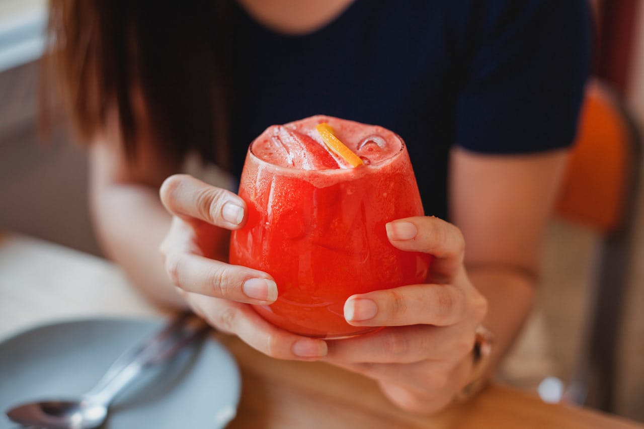 Woman holding a refreshing berry cocktail in a cozy café, perfect for leisure and relaxation.